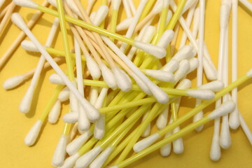 Cotton made ear buds all together close display on yellow background. 