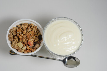 Yogurt in a beautiful glass bowl next to a box of granola and a spoon.