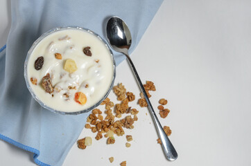Yogurt in a beautiful glass bowl next to a box of granola and a spoon.