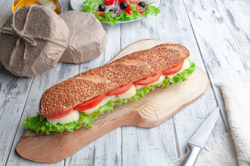Sandwich with Adyghe cheese, lettuce and tomatoes. On a wooden board.