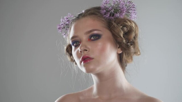 Portrait of a pretty girl on a light background, studio shooting on the theme of spring, girl with flowers in her hair.