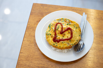 
Omelette on a white plate with red heart-shaped sauce