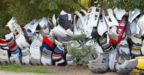 Pile of discarded damaged fenders or bumpers in scrapyard