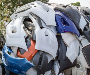 Pile of discarded damaged fenders or bumpers in scrapyard