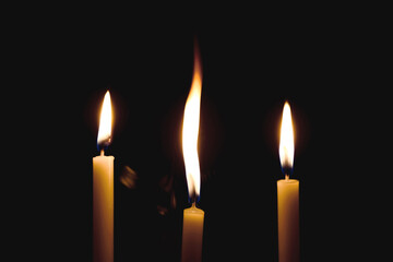White Candles Burning in the Dark with lights glow, The burning candle's flame in the dark background,  a symbol of the Christian faith, Candles Burning in the Dark with lights glow.