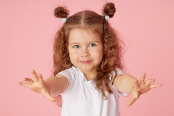 Portrait of surprised cute little toddler girl child over pink background. Looking at camera. Points hands to the left side. Advertising childrens products