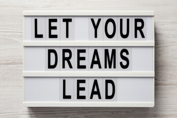 'Let your dreams lead' on a lightbox on a white wooden background, top view. Flat lay, from above, overhead.
