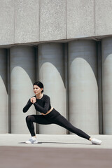 Street training on the embankment of a beautiful girl stretching her inner thigh muscles with squats and lunges sideways