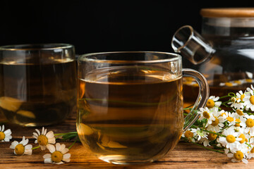 Cup of tea and chamomile flowers on wooden table
