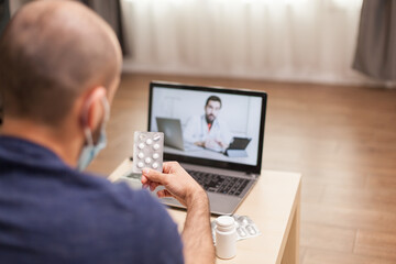 Adult man on video conference with doctor about ill treatment during global pandemic.
