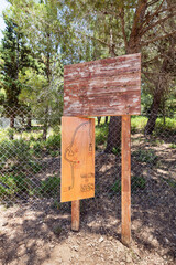 Wooden  signs in English, Hebrew and Arabic with a drawn map and opening hours of the monastery of Lavra Netofa near the village of Hararit in northern Israel