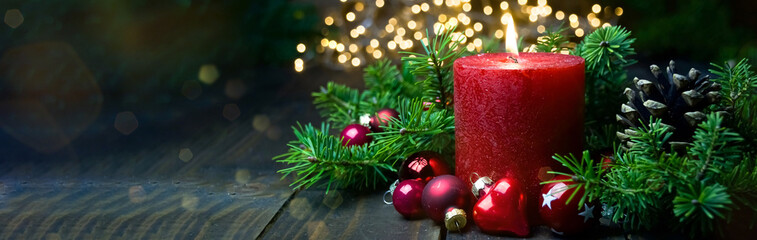 Red burning advent candle with christmas balls and golden bokeh lights - christmas background...