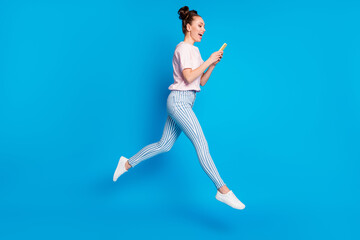 Fototapeta na wymiar Full length body size view of her she nice-looking attractive pretty lovely glad cheerful cheery girl jumping using digital device 5g app isolated on bright vivid shine vibrant blue color background