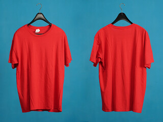 Exclusive hanger with empty red t-shirt hanging isolated on a blue background. Blank red male...