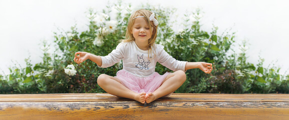 panorama - little girl in yoga pose in green garden