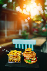 Burger and crispy French Fries and onion rings on cafe table