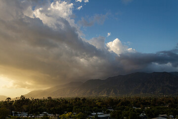 The sun sets behind clouds over the San Gabriel Mountains of Southern California