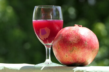 Pure health: freshly squeezed pomegranate juice in a glass with a whole ripe pomegranate fruit
