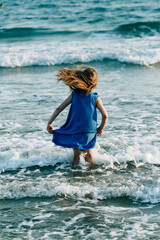 Fototapeta premium girl in a blue dress in the sea in the waves
