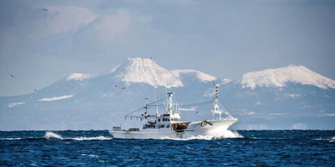 Fishing boat returns after fishing to its port. Against the backdrop of the island of Kunashir....