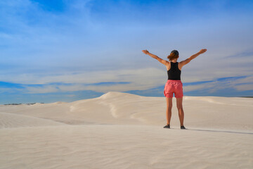 Fototapeta na wymiar Woman walking through sandy desert dunes.