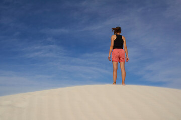 Woman walking through sandy desert dunes.