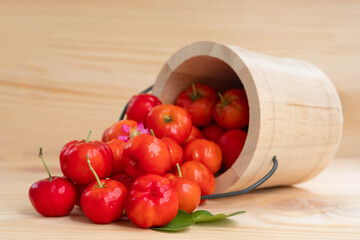 Acerola cherry in wooden bucket on wooden background. Select  focus, Barbados cherry, Malpighia emarginata, high vitamin . Acerola fruit.