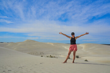 Woman walking through sandy desert dunes.
