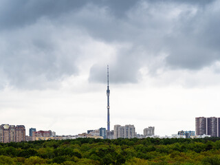 Obraz premium gray rainy clouds over residential district of Moscow city, TV tower and green park in spring