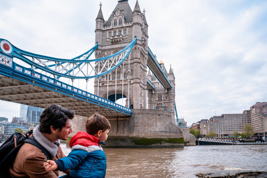 Father and son throwing stones in River Thames  next to Tower Bridge