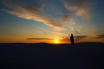 Fototapeta na wymiar A woman standing against the backdrop of the setting sun
