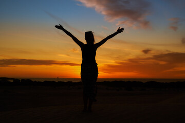 Fototapeta na wymiar A woman standing against the backdrop of the setting sun