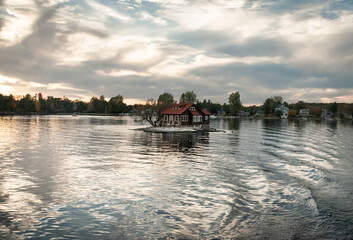 Fototapeta premium sunset on the river, small island floating house, waves, water reflection in 1000 islands
