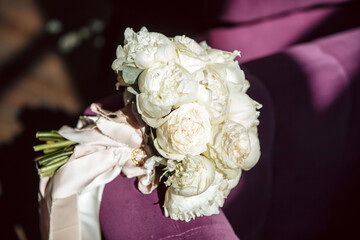 A bouquet of flowers lies on a purple cloth. Wedding rings in a glass box. Wedding concept. Wedding trend