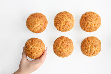 Children's hand takes one of the cupcakes located on a white background, shot from above