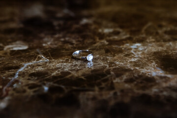 A diamond ring rests on marble. Wedding minimalism.