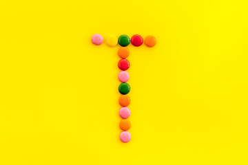 Letter T - alphabet made with sweets on yellow from above