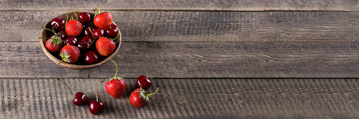 Wooden bowl with summer food berries. Strawberry and cherry in plate on wooden table background....