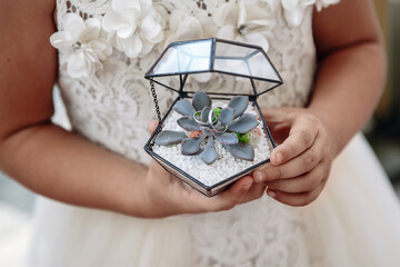 The child's hands hold a box with a flower and rings.