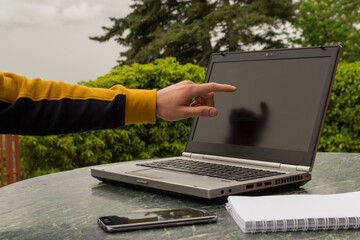 a young student pointing at a laptop at his outdoor work table