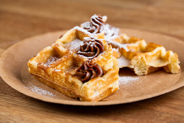 Viennese waffles on a disposable plate with peanut butter, icing sugar and mint.