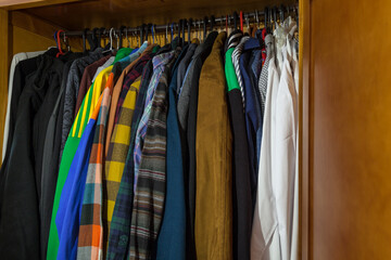Wardrobe full of clothes of different styles on hangers. Concept of changing the wardrobe by season, second-hand sales and sales in the textile sector with negative space.