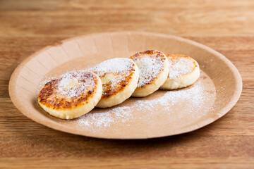 fried cheesecakes on a disposable plate with icing sugar