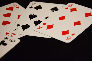 Deck of cards with spades, diamonds, hearts and clubs over a black background