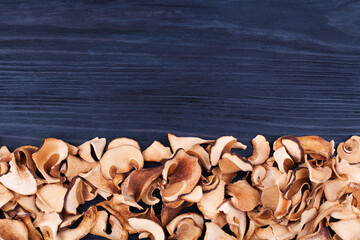 Fototapeta na wymiar Edible dried mushrooms border black wooden background close up top view, dry boletus edulis dark wood backdrop frame, brown cap boletus, penny bun, cep, porcino, porcini, white fungus, text copy space