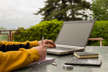a young student works with his laptop at his outdoor work table