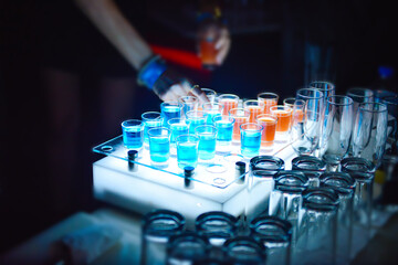 Variation of hard alcoholic shots served on bar counter, Blue and orange alcohol shots in club