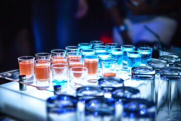 Variation of hard alcoholic shots served on bar counter, Blue and orange alcohol shots in club