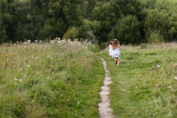 children run away along the path in the park, the concept of summer and childhood, child safety.