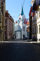 Empty street of Old Riga Town with sharply white Our Lady of Sorrows Church. City center in coronavirus COVID-19 pandemic quarantine time.
